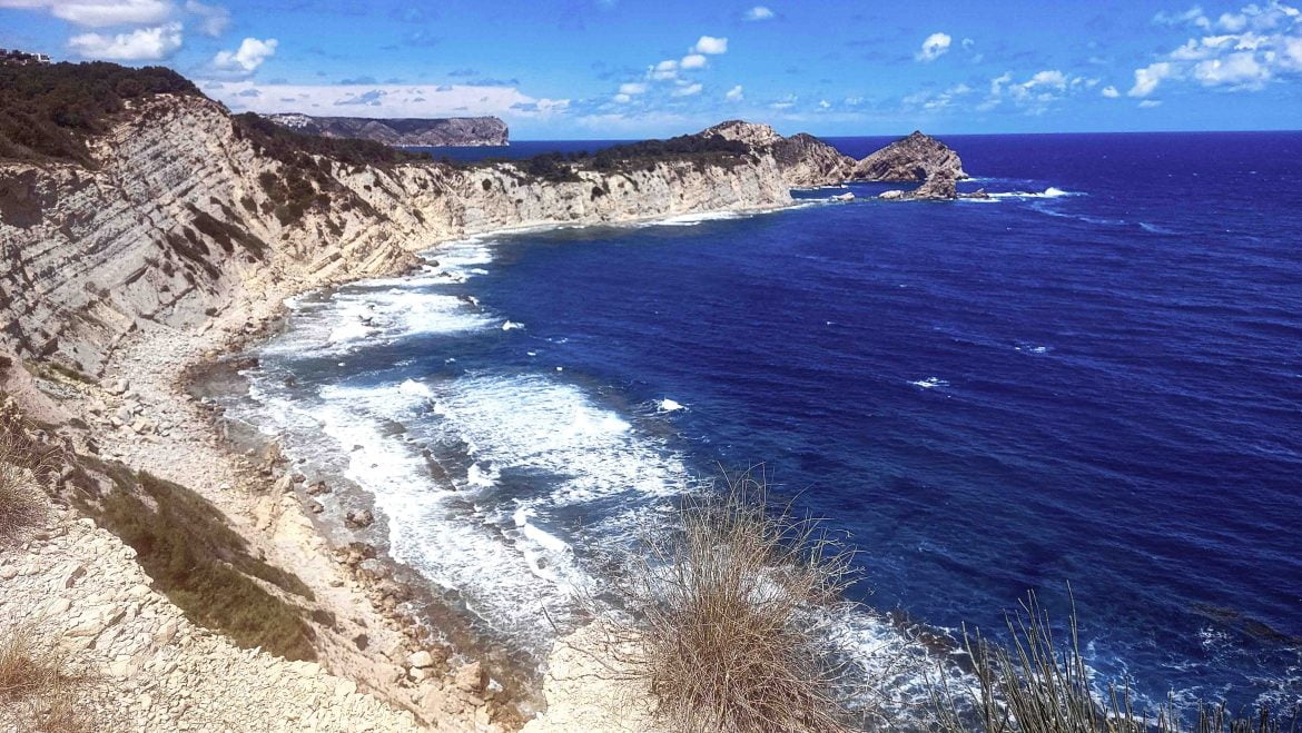 Playa del Portixol y, al fondo, el Cap Prim, así como el Cabo de San Antonio